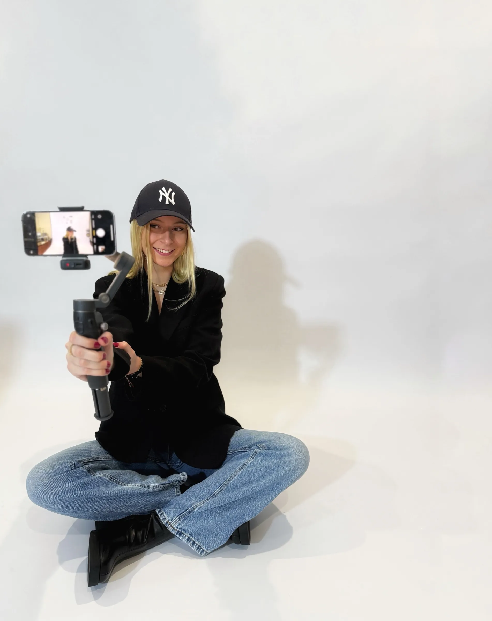 Fanny assise en studio, en train de se filmer avec son téléphone sur une perche